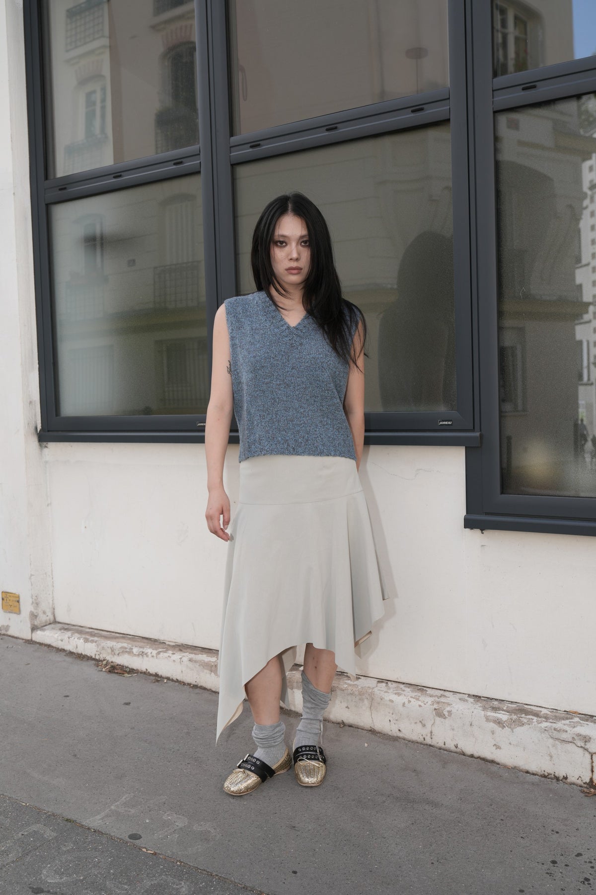 Model wearing the MIST AW26 blue textured V-neck knitted vest, styled with a light skirt.