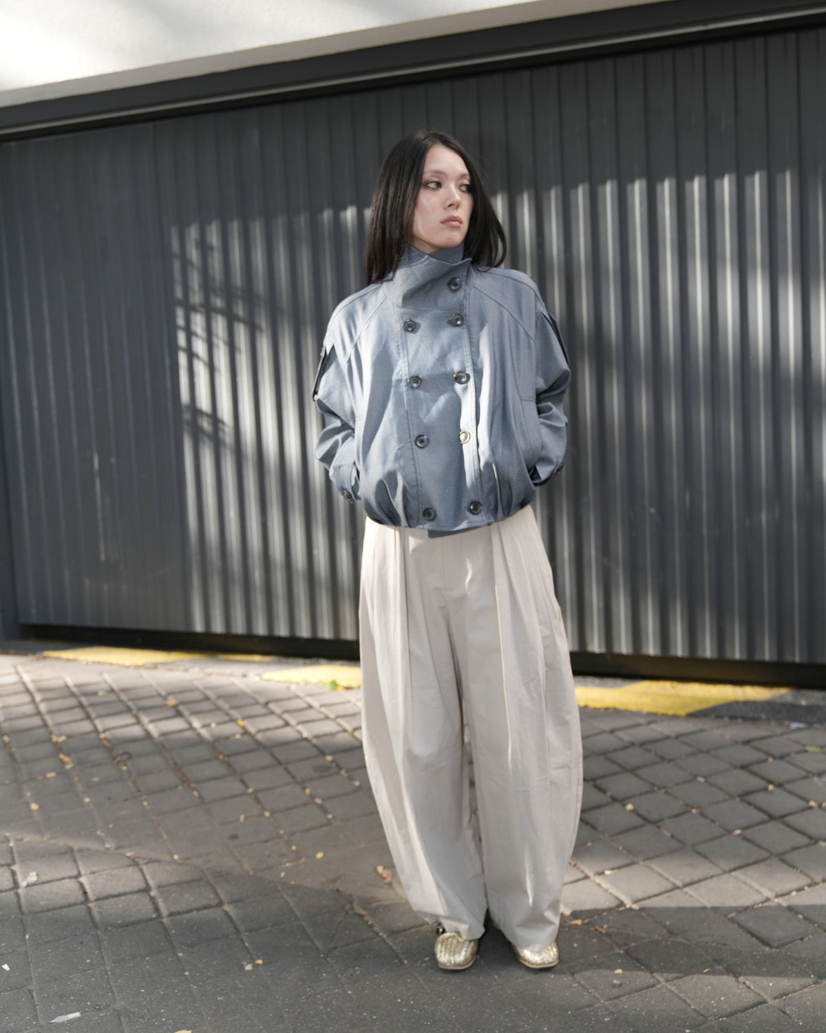 MIST model wearing a blue-grey jacket and cream wide-leg trousers in Paris.